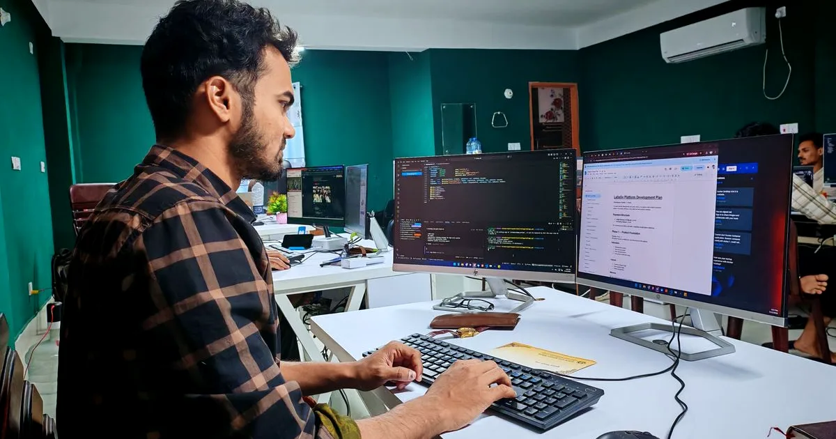 Software developer working at a dual-monitor setup in a modern office